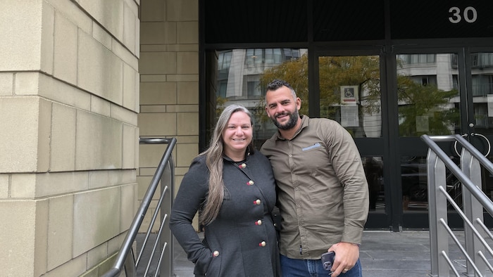 Christine Hallé et son mari posent pour la photo devant l'entrée de l'édifice de la Cour fédérale.