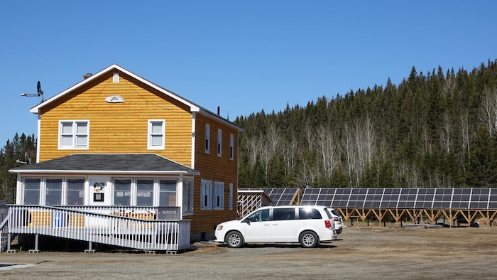 Un bâtiment en bois rond avec des panneaux solaires à l'arrière.