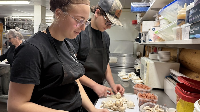 Deux personnes travaillent dans la cuisine d'un restaurant.