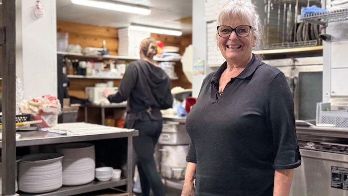 Une femme se tient debout dans la cuisine d'un restaurant.