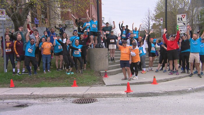 Des participants expressifs qui attendent l'arrivée des coureurs à une station du parcours.