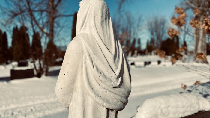 Une statue de la vierge dans un cimetière.