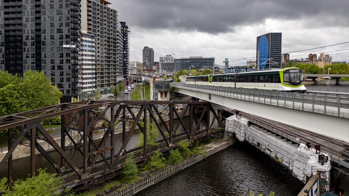 Vue aérienne du train Réseau express métropolitain (REM) alors qu'il quitte la ville de Montréal.