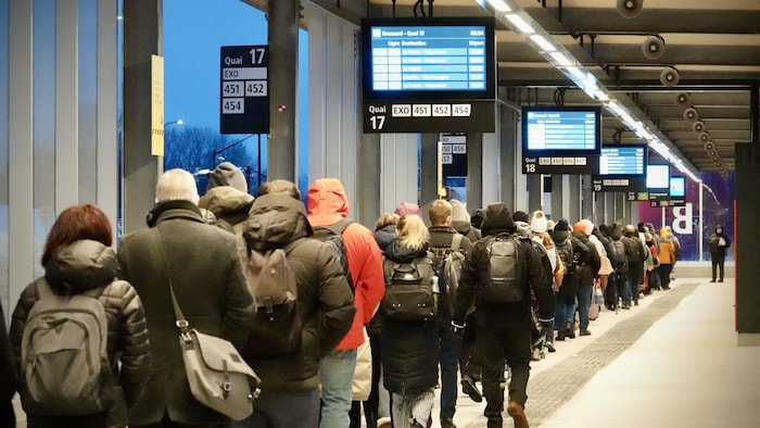 Une longue queue de passagers dans une gare du REM.