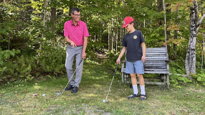 Rémi Jean et lad   petit-fils Émile jouent au golf.