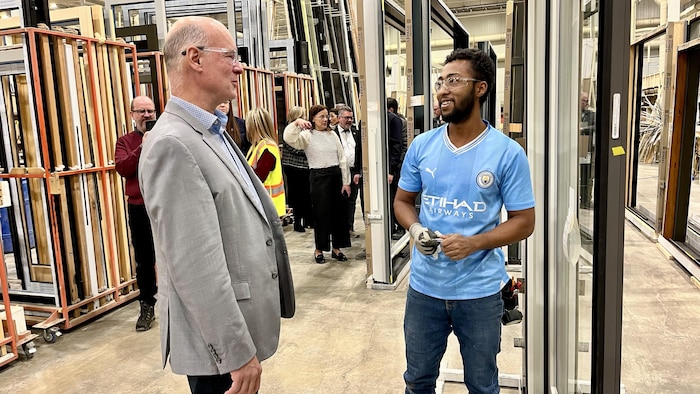 Un candidat à la campagne électorale discutant avec un employé d'une usine.