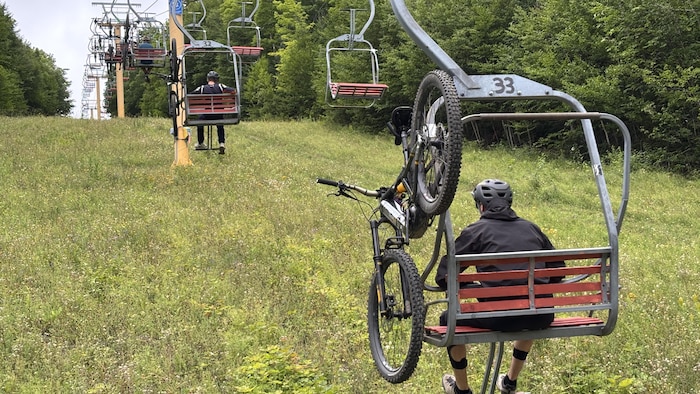 Des cyclistes sont dans un remonte-pente au Mont-Comi.