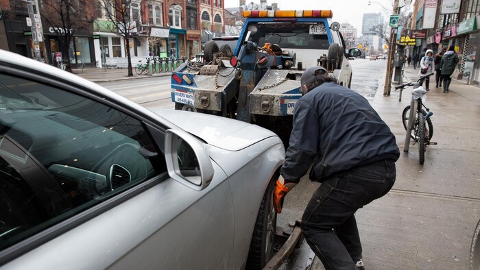 Une voiture est remorquée sur la rue Queen à Toronto.