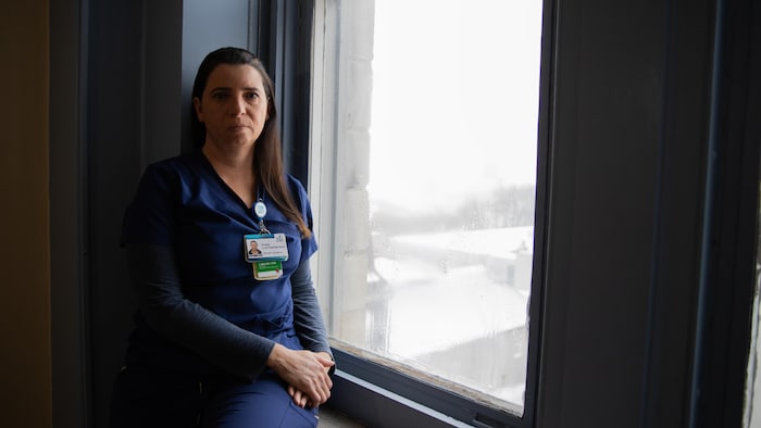 Une personne assise près d'une fenêtre.