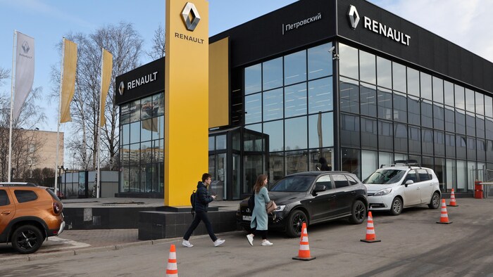 Un homme et une femme marchent près d'un concessionnaire Renault. 