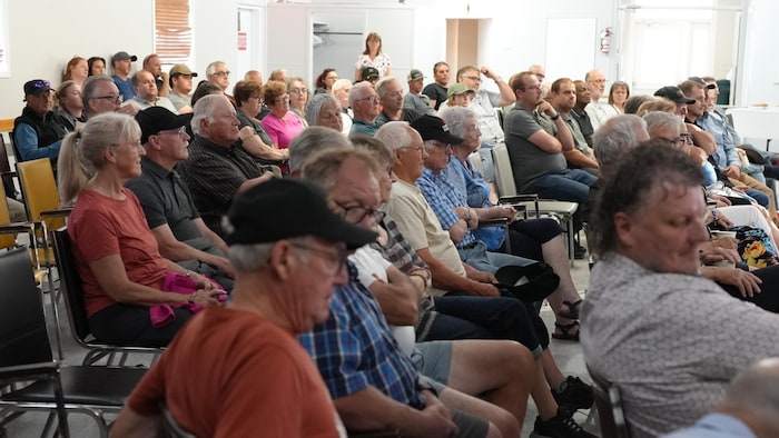 Des gens assis dans une salle écoutent une présentation.