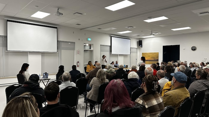 Un groupe de personne assises face à une table de cinq personnes. 