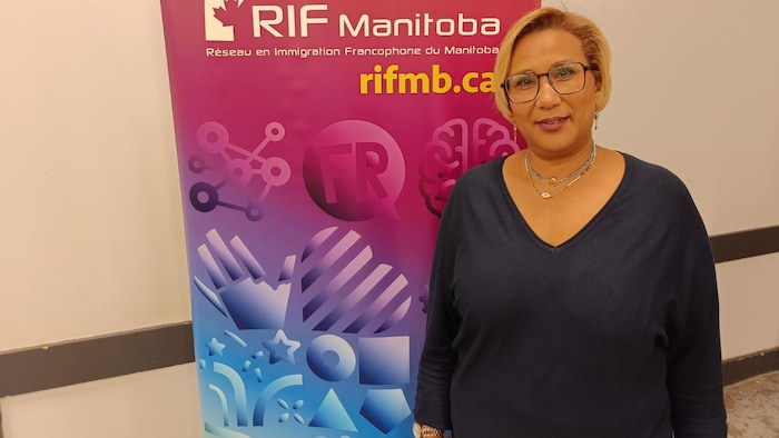 Une femme debout devant une bannière du RIF Manitoba.