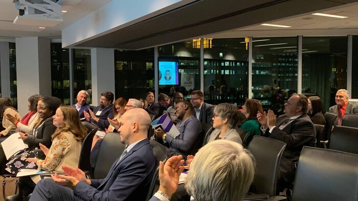 Des gens d'affaires assis dans une salle qui applaudissent.