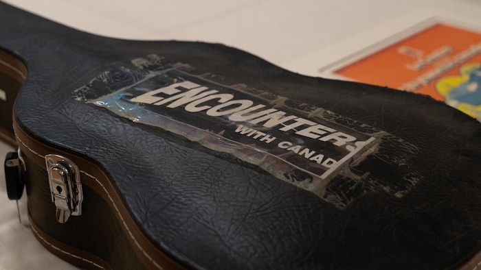 Un étui de guitare arborant un autocollant de Rencontres du Canada.