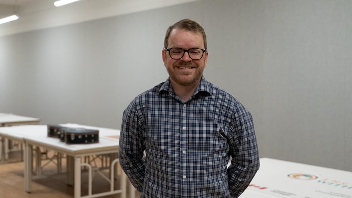 James Trépanier dans une salle qui contient des objets de Rencontres du Canada.