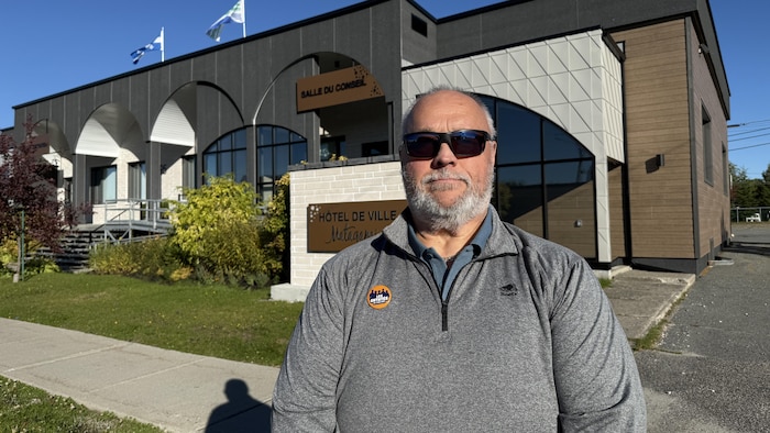 René Dubé devant l'Hôtel de ville de Matagami. Il porte un macaron du mouvement Les Entêtés de l’Administration régionale de la Baie-James.