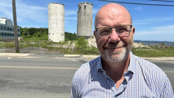 Un homme sourit devant l'objectif, la papetière derrière lui.