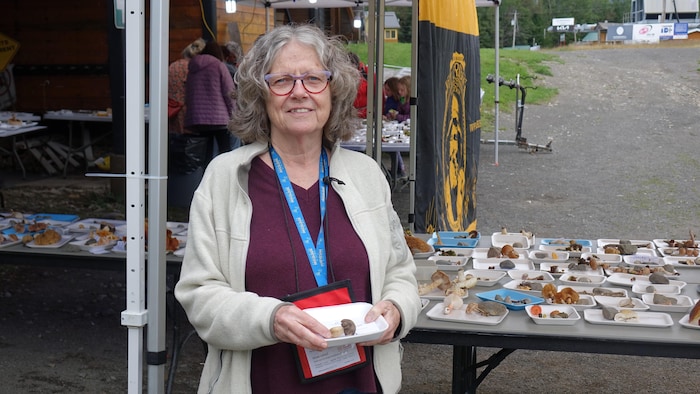 Portrait de Renée Leboeuf devant une table de champignons.