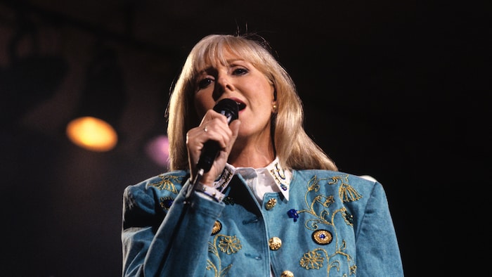 Renée Martel chante, micro à la main.