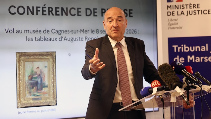 Un homme devant un lutrin parle dans des micros.