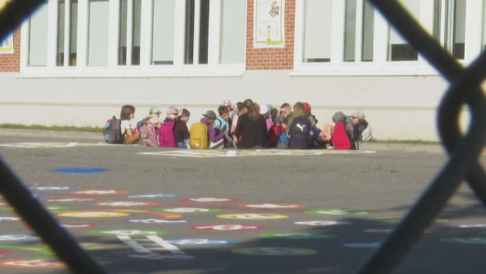Des élèves en rond sur le sol, dans un cour d'école.