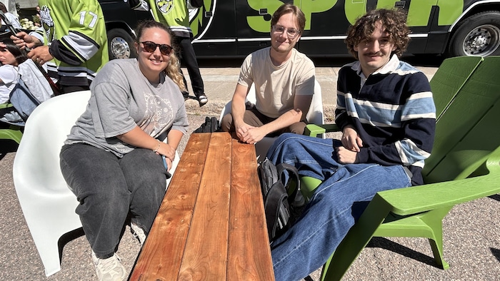 Trois étudiants assis sur des chaises.