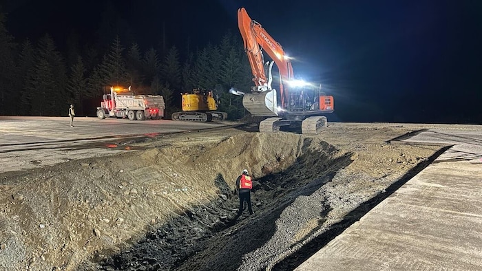 Un homme et des engins de chantier sur une route en travaux.