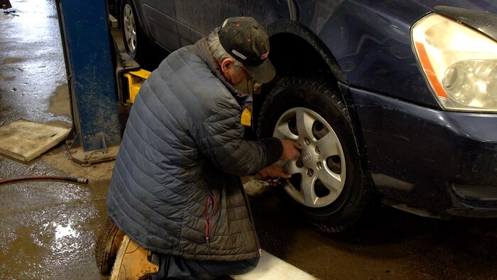 Un garagiste qui remet des vis sur la jante d'un pneu.