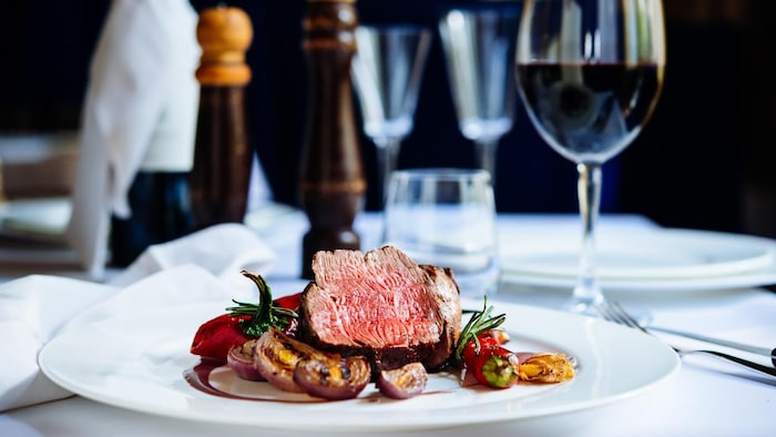 Une assiette de bœuf et de légumes et un verre de vin rouge sur une table de restaurant
