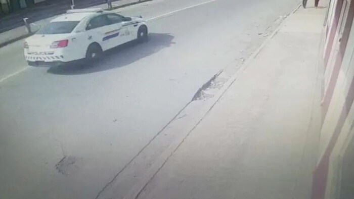 La voiture du tireur qui passe près d'un commerce.