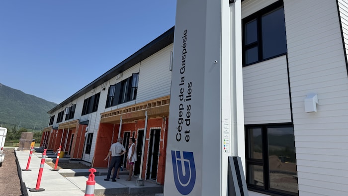 L'extérieur des nouvelles résidences étudiantes du Cégep de la Gaspésie, avec des montagnes au fond et des cônes de chantier au premier plan.