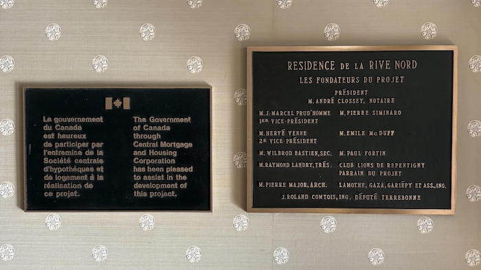 Sur la plaque de gauche, on peut lire : Le gouvernement du Canada est heureux de participer par l'entremise de la Société centrale d'hypothèques et de logement à la réalisation de ce projet. La plaque de droite mentionne les fondateurs du projet dont le Club Lions de Repentigny, parrain du projet.