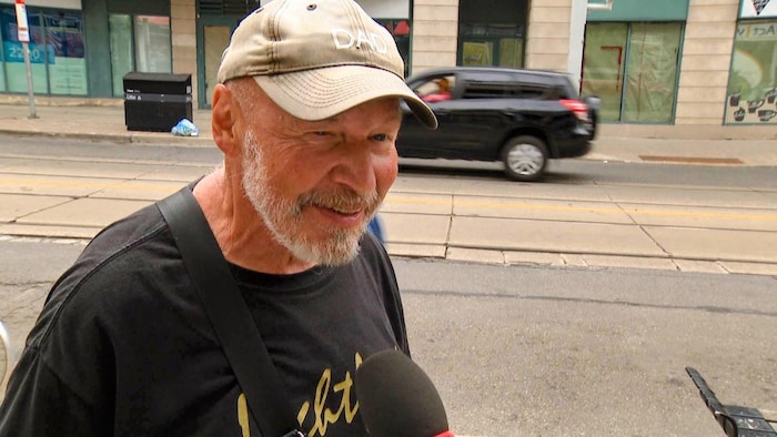 Peter Schindler répond aux questions d’une journaliste dans une rue.
