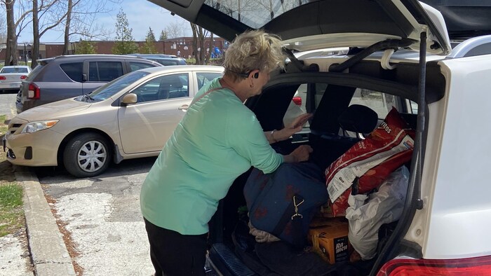 Une personne met des provisions dans sa voiture