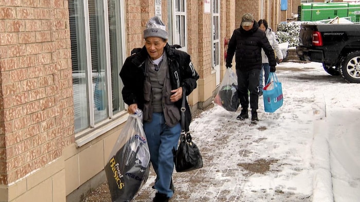 Des résidents transportant des sacs et des valises en se dirigeant vers la porte d’entrée du 11, rue Thorncliffe Park.