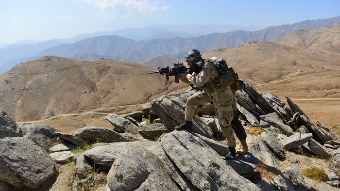 Deux hommes armés braquent leur fusil au sommet d'une montagne.