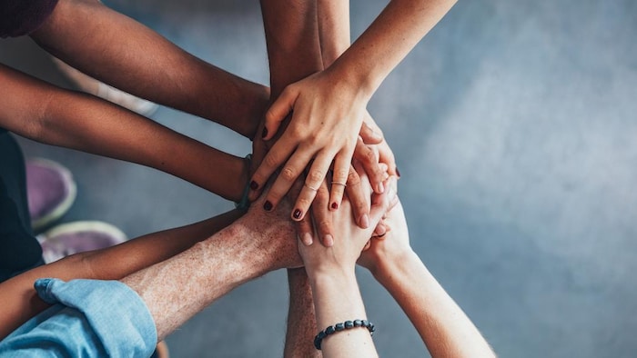 Six personnes unissent leurs mains les unes sur les autres.