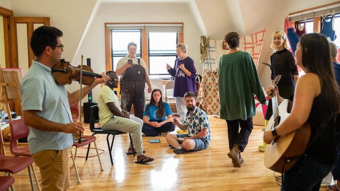 Des gens dansent et écoutent de la musique dans un grenier. 