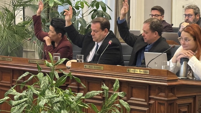Trois élus de Respect citoyens lèvent la main pour voter contre le budget de l'année 2026 à l'hôtel de ville de Québec.