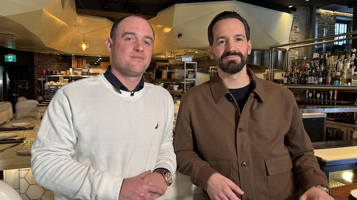 Deux personnes posent devant la caméra dans un restaurant.