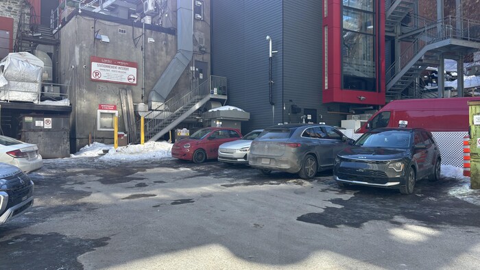 Un stationnement extérieur où des véhicules sont stationnés.