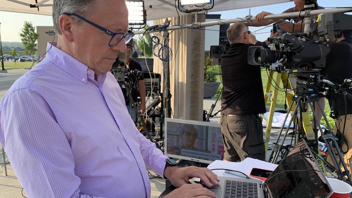 Marc André Masson, à l'extérieur, tape sur un portable.