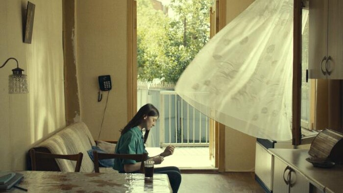 L'actrice Ani Karseladze assise sur un canapé dans une cuisine dans le film d’Alexandre Koberidze.