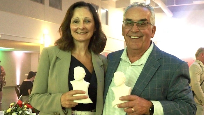 Carole Freynet-Gagné et Louis Tétrault tiennent une statuette de Louis Riel.
