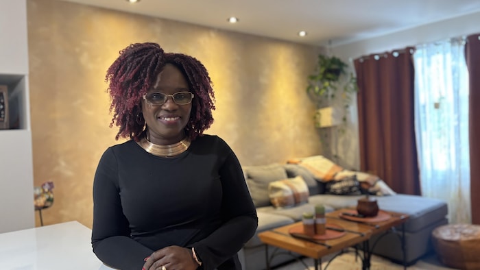 Une femme pose dans son salon.