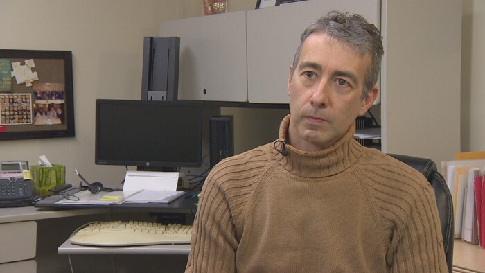 Un homme parle à la caméra dans son bureau.