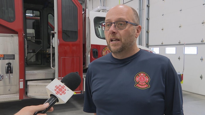Rhéal Gagnon, chef du service d'incendie de La Broquerie, s'exprime devant un camion pompier.