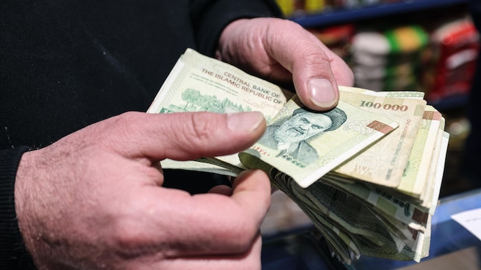 Un commerçant compte des billets de banque iraniens dans un magasin de la capitale Téhéran, le 7 janvier 2026.