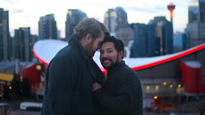 Ricardo Miranda et Christopher Brown prennent une photo devant le Saddledome de Calgary.